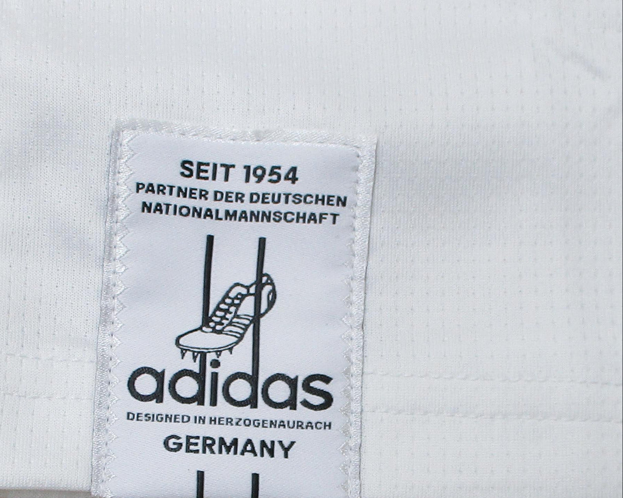 Deutschland Nationalmannschaft Trikot WM 2026 Adidas Herren mit gesticktem DFB Wappen und Adidas Logo AEROREADY Technologie neu mit Etiketten. Detailansicht Adidas Logo Saum.