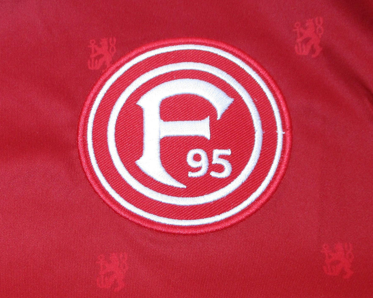 Rotes offizielles Fortuna Düsseldorf Heimtrikot 2020/21 von Uhlsport in Herrengröße. Detailansicht Wappen.